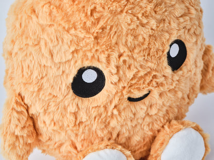 Adorable Chicken Nugget plush toy with fuzzy texture, small arms and legs, and a happy embroidered face staring into the camera in a close up