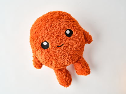Adorable Spicy Chicken Nugget Orange plush toy with fuzzy texture, small arms and legs, and a happy embroidered face lying on a white surface.